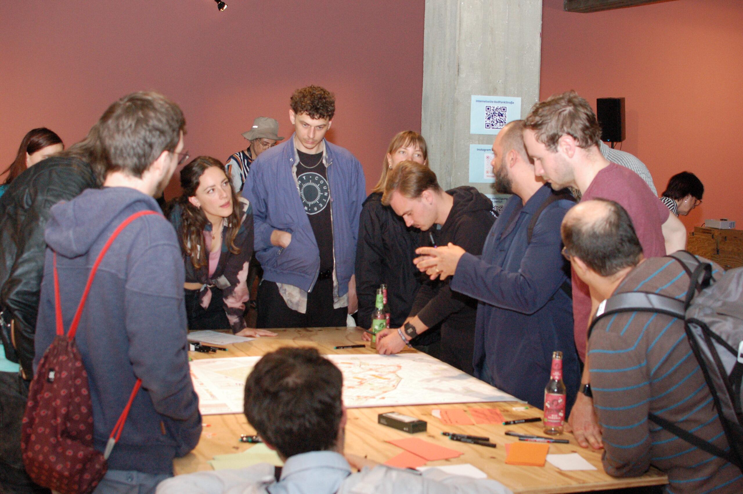 Eine Gruppe von Menschen versammelt sich um einen Tisch und diskutiert die Bestandsanalysepläne des Fördergebiets.