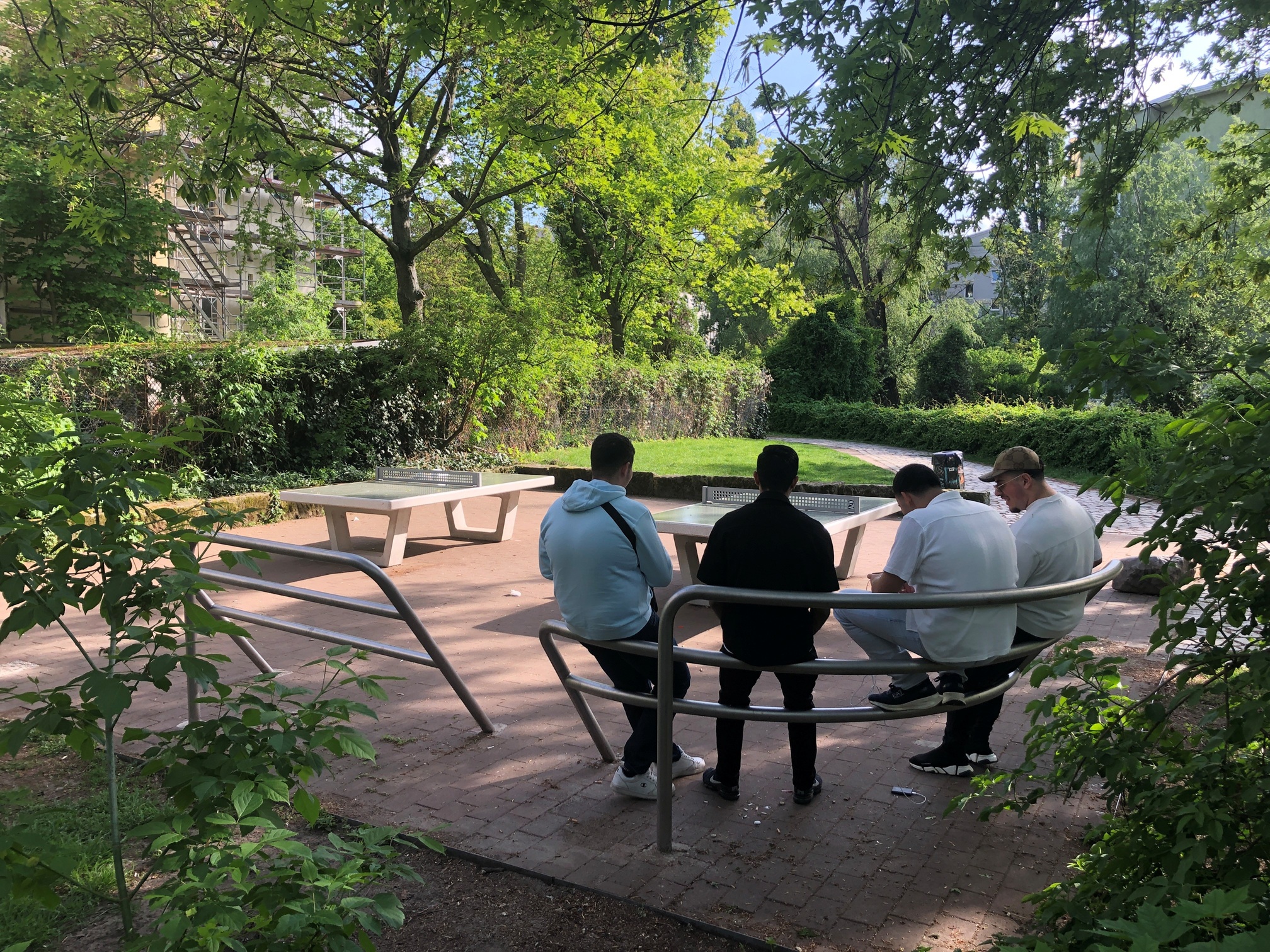 Vier Jugendliche sitzen auf Jugendbänken am neu gestalteten Tischtennisplatz.